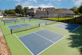 two tennis courts with houses in the background on a sunny day