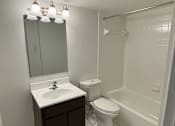 Thumbnail 18 of 26 - A bathroom with a toilet, sink, and mirror.