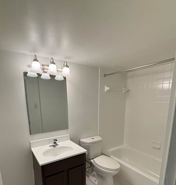A bathroom with a toilet, sink, and mirror.