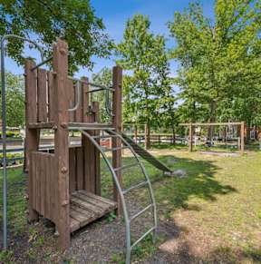 A playground with a wooden swing set and a metal slide.