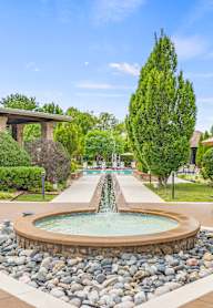 a fountain in the middle of a yard with a house in the background at Avignon Apartment Homes, Olathe, KS