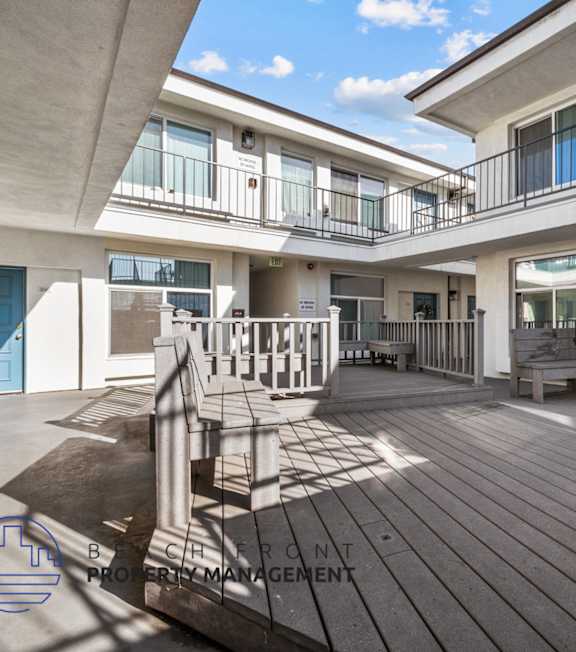 A pool with a hot tub and lounge chairs in front of a building.