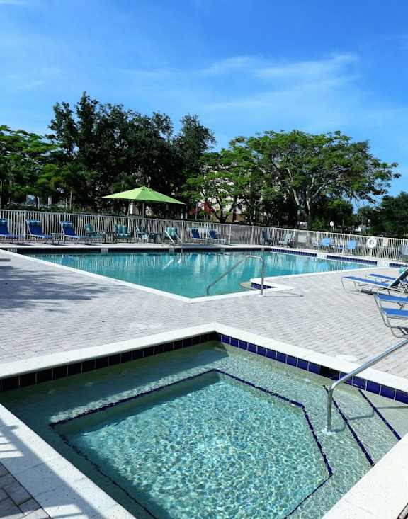 A pool with a small pool in the middle and chairs around it.