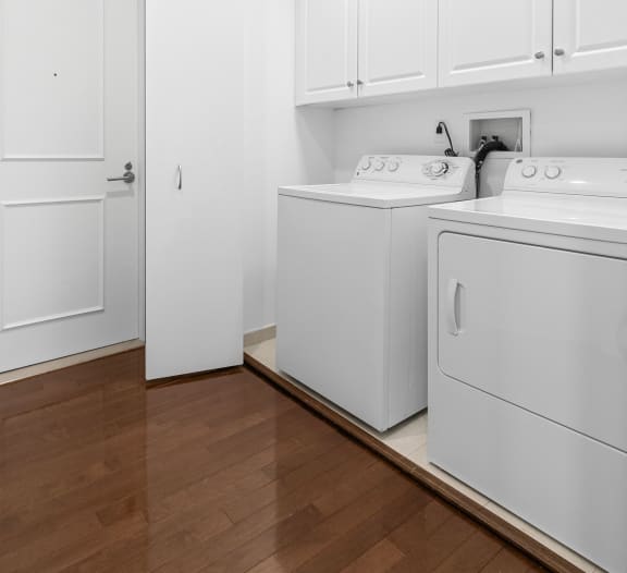 a washer and dryer in a room with white cabinets and a wood floor at HIGHGROVE, Stamford, CT