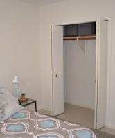 A bedroom with a bed, pillows, a nightstand, and a wardrobe.