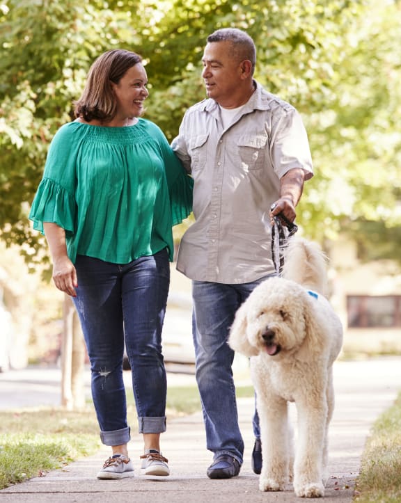 a man and a woman walking a dog down a sidewalk
