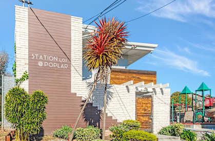 A building with a sign that says "STATION @ POPULAR" is surrounded by plants and a playground.