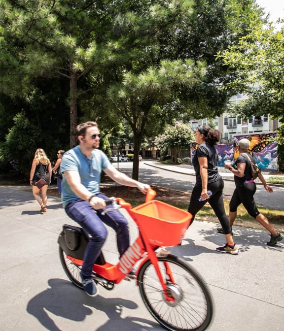 Man riding bike on The Atlanta Beltline, adults in background excersing and walking on beltine in Atlanta, GA