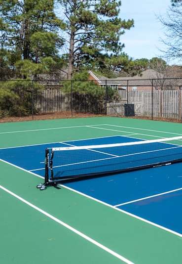 A tennis court with a net and a green and blue surface.