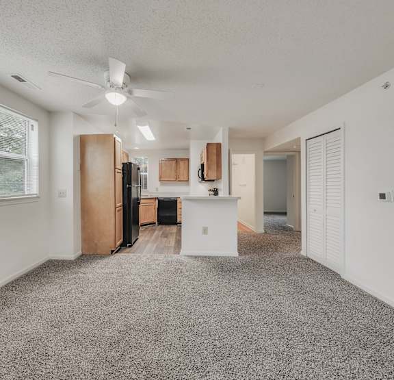  A spacious kitchen with a refrigerator, cabinets, and a ceiling fan.