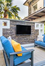 A modern outdoor living space with a stone wall and a television.