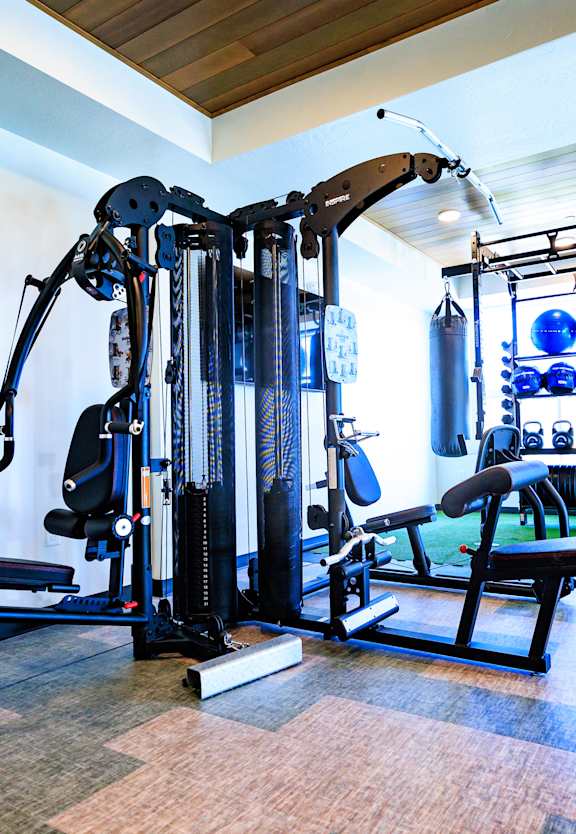 A gym with a variety of equipment including a leg press machine, a cable machine, and a bench press.