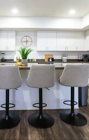 a kitchen with white cabinets and a counter with chairs