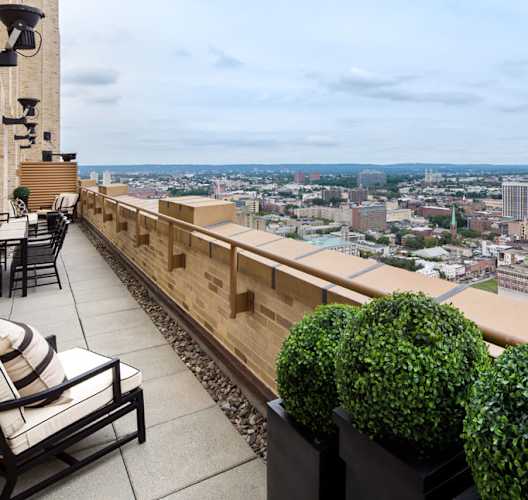 a view of the city from a balcony with chairs and plants