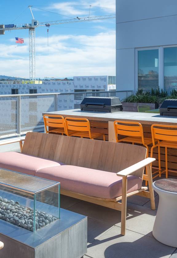 A modern outdoor seating area with a glass table and chairs.