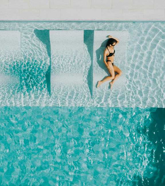 A woman is floating on a pool with her arms outstretched.