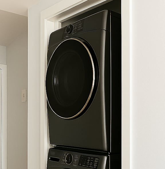 A black front loading washing machine in a white wall.