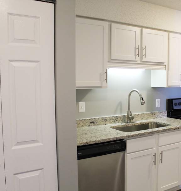 A kitchen with white cabinets and a black stove top oven at The Avery at Auburn Apartments in Auburn, AL