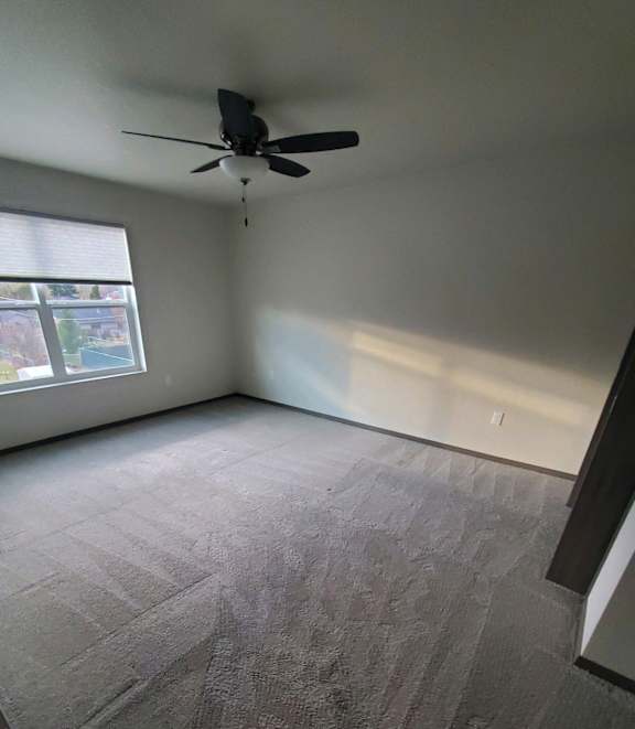 A room with a ceiling fan and a window.