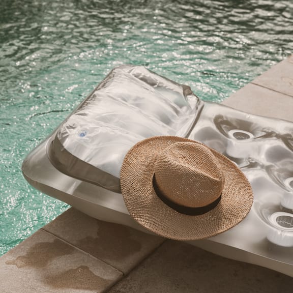 A hat is placed on a sun lounger by the pool.