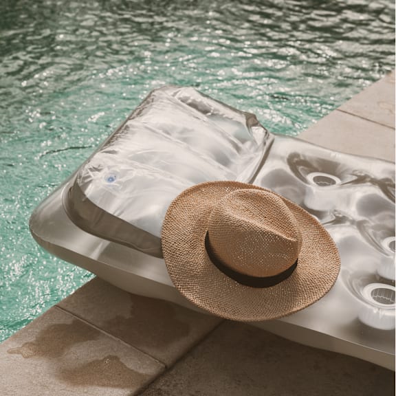 A hat is placed on a sun lounger by the pool.