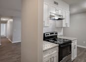 Thumbnail 2 of 34 - A kitchen with a stove top oven and a range hood.