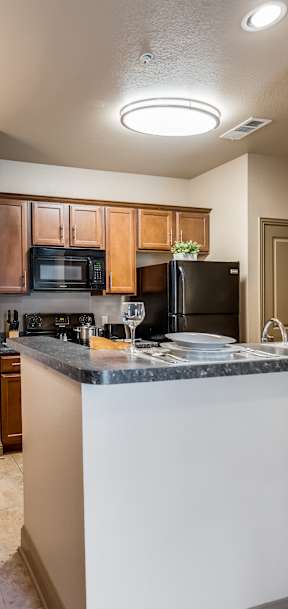 A kitchen with a table and chairs in the foreground and a microwave and refrigerator in the background.