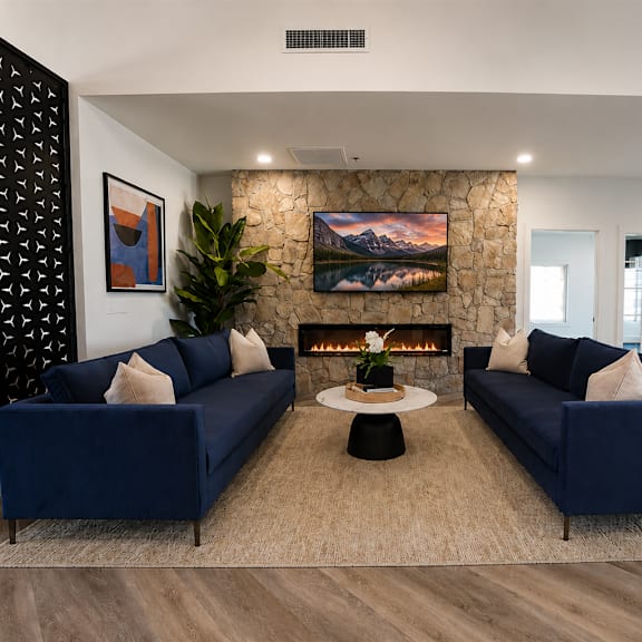 A living room with two blue couches and a fireplace.