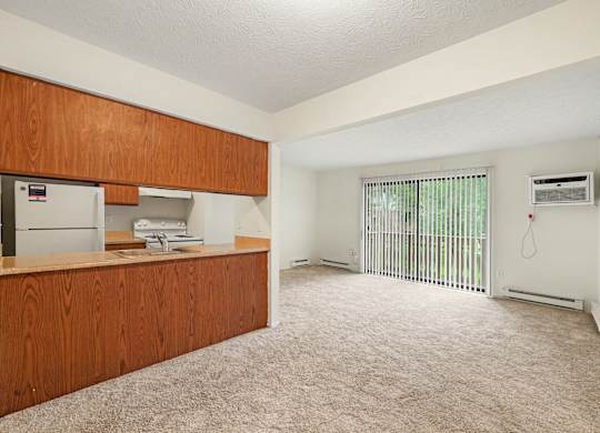 A room with a brown wooden cabinet and a white fridge.