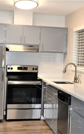 a kitchen with stainless steel appliances and white counter tops at Trailhead Apartments at Tam Junction, Mill Valley, CA