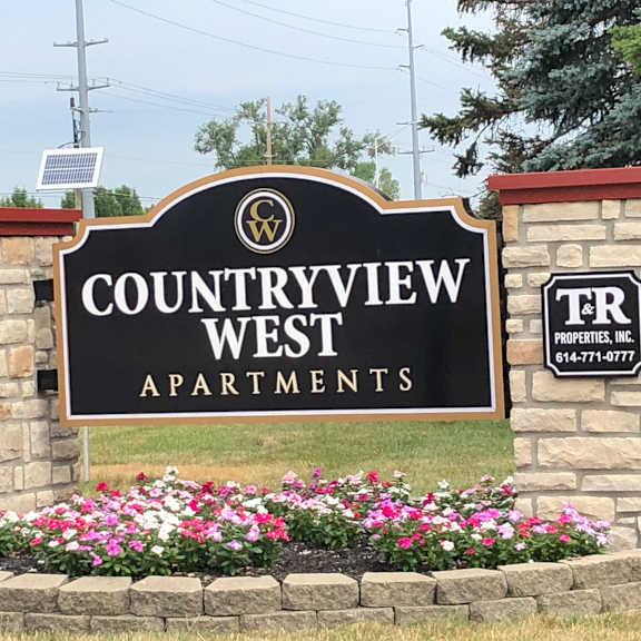 A sign for Countryview West Apartments is displayed in front of a flower bed.