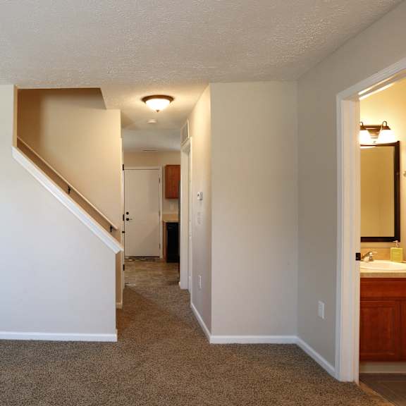 A hallway with a staircase and a bathroom.