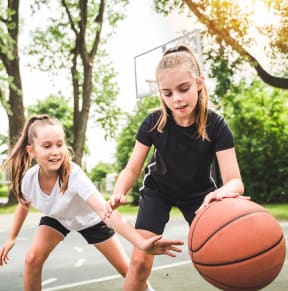 two girls playing basketball on a court