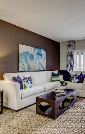 A living room with a white couch and a painting on the wall.