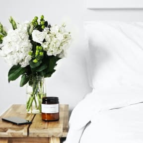 A bedside table with a vase of flowers and a cell phone on it, adding a personal touch to the bedroom.