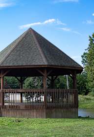 A gazebo sits in a grassy area next to a body of water.