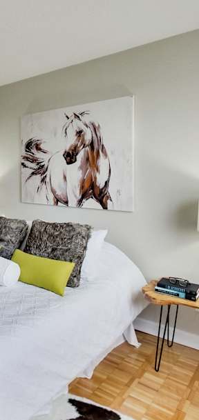 a bedroom with a white bed and a painting on the wall