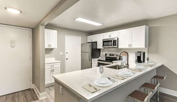 A kitchen with a white counter top and stainless steel appliances.