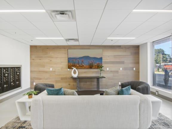 a living room with a couch and a table in front of a wooden wall