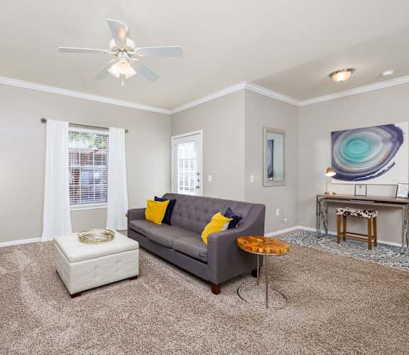 a living room with a gray couch and a white ottoman