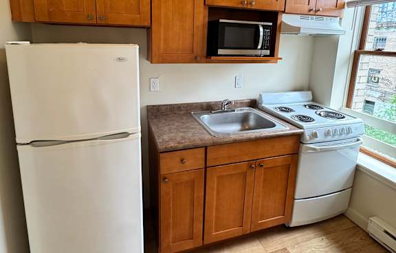 A kitchen with wooden cabinets and a white fridge.