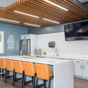 a kitchen with an island and orange chairs