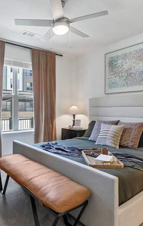 A bedroom with a large bed and a ceiling fan.