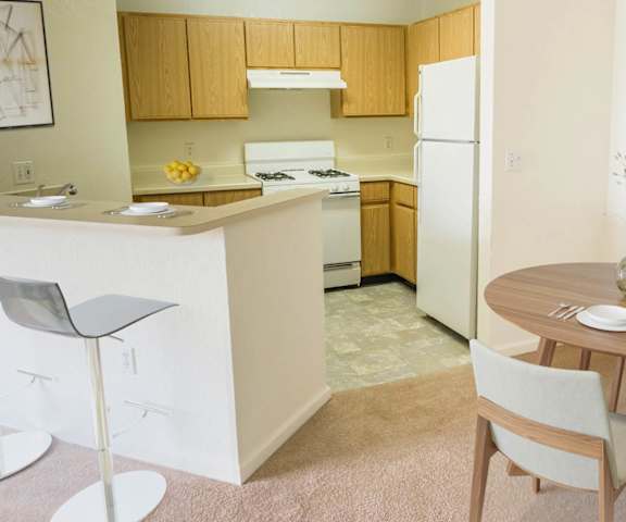 A kitchen with a table and chairs in the foreground and a refrigerator in the background.
