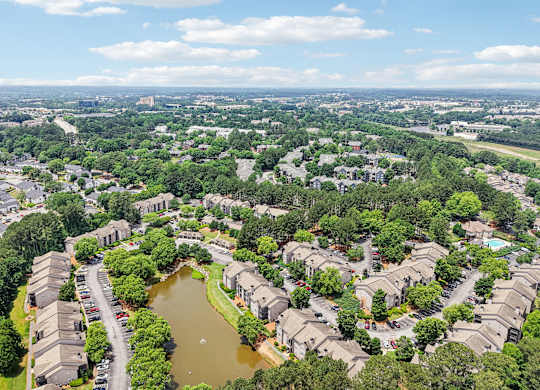 A bird's eye view of a residential area with a pond in the middle.