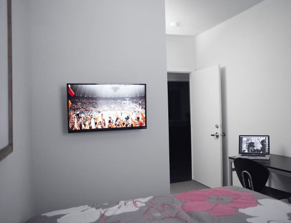 a bedroom with a tv on the wall and a bed