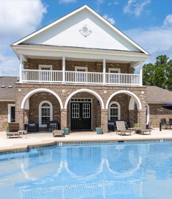 A pool in front of a house with a balcony.