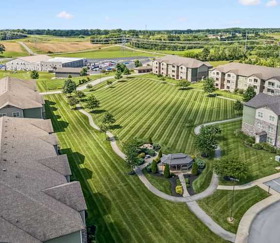 A large grassy area with a building on the left and apartment buildings on the right.