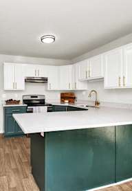 A kitchen with white cabinets and a green island.
