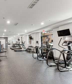 A spacious gym with a variety of equipment including treadmills, stationary bikes, and weight machines.